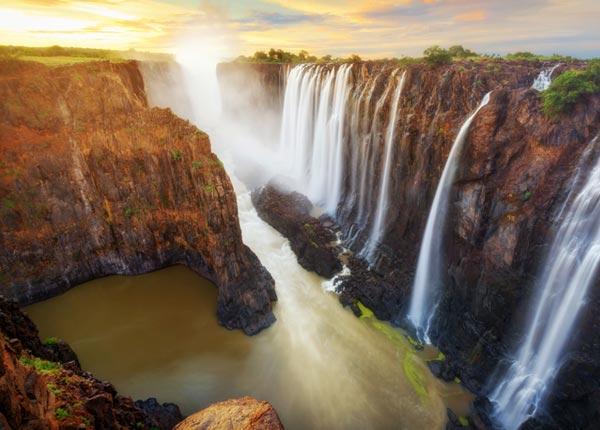 single traveler in awe of her surroundings with the view over Victoria falls in Zambia and Zimbabwe