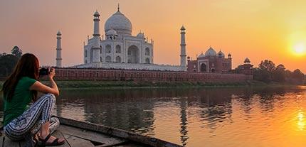 Solo Traveller in India taking a photo of a perfect sunset with the Taj Mahal in the foreground Singles tours, solo tours around the world with Tucan Travel. Explore the world with Tucan Travel on a solo adventure India, Asia