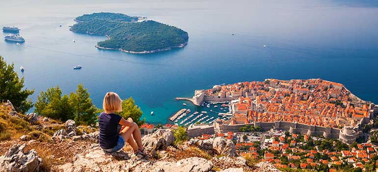 Traveller overlooking historic Dubrovnik in Croatia croatia is one of the best places to travel in August, holidays in August, Travel calendar