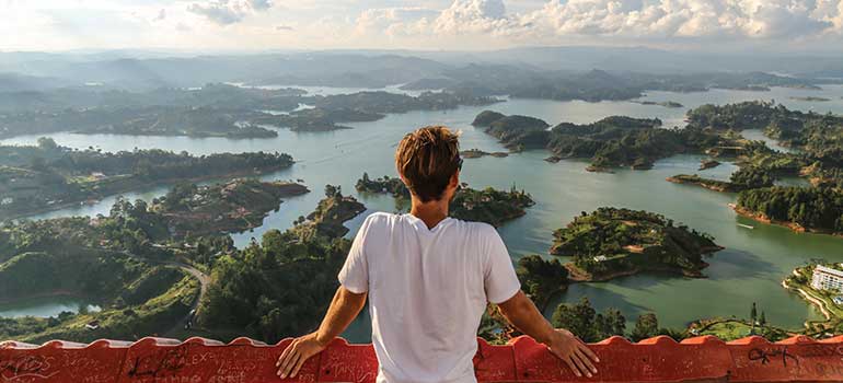 Traveller enjoying the view over Guatape, a day trip from Medellin Colombia is one of the best places to visit in February, February holiday, where to go in February