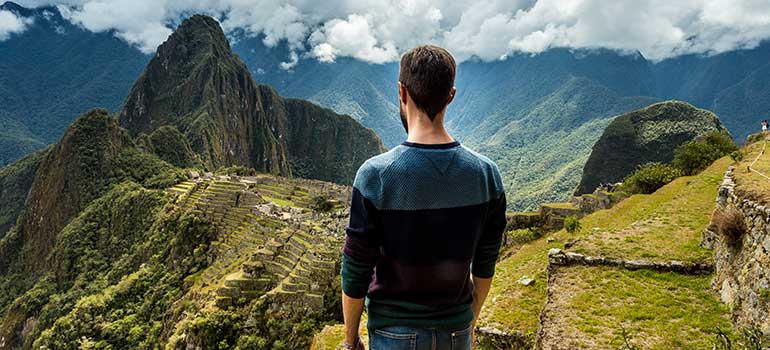 Traveller overlooking iconic Machu Picchu in Peru machu picchu is one of the best places to visit in July, adventures in July