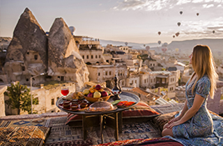 Solo female on a soft cushions on the open veranda and looks at the panorama of Cappadocia, Turkey