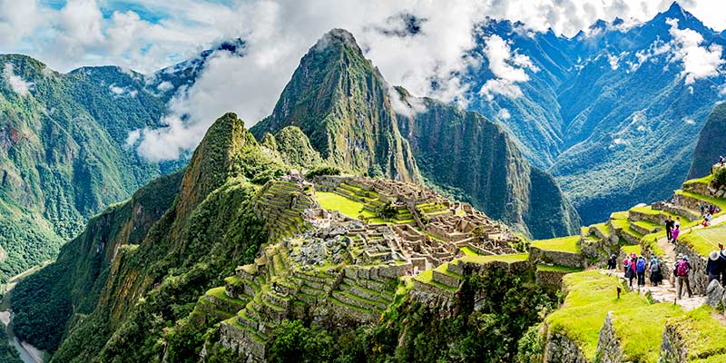Tourists on vacation sightseeing the ancient ruins of Machu Picchu one of the wonders of the world and top bucket list sights when visiting Peru