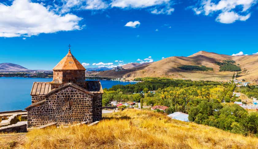 Scenic view of an old Sevanavank church in Sevan, Armenia on sunny day blue sky and fluffy clouds