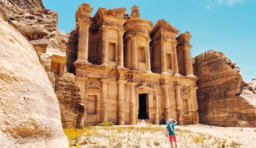 A man stands in front of the Monastery in the desert of Petra